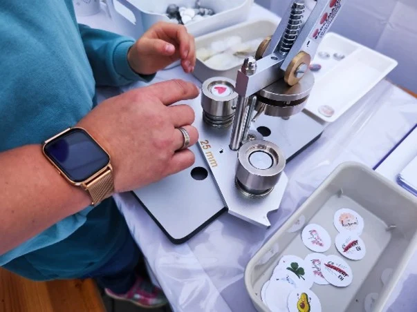 Foto von einer Frau an einer Buttonmaschine
