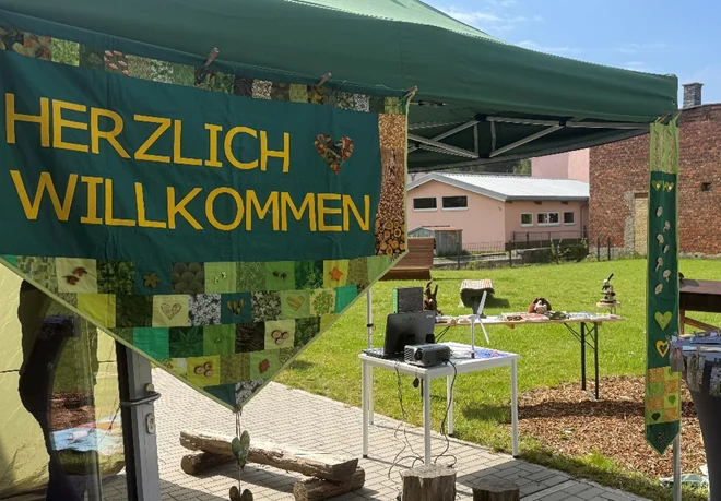 Foto von einem Stand mit dem Schild »Herzlich Willkommen«
