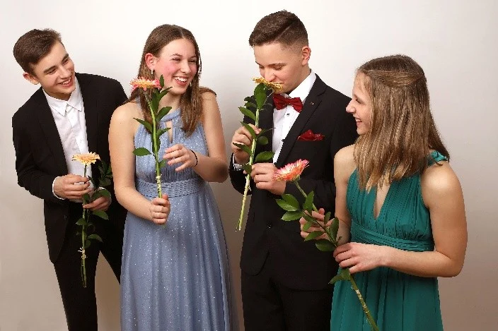 Jugendliche in Festkleidung mit Blumen in der Hand