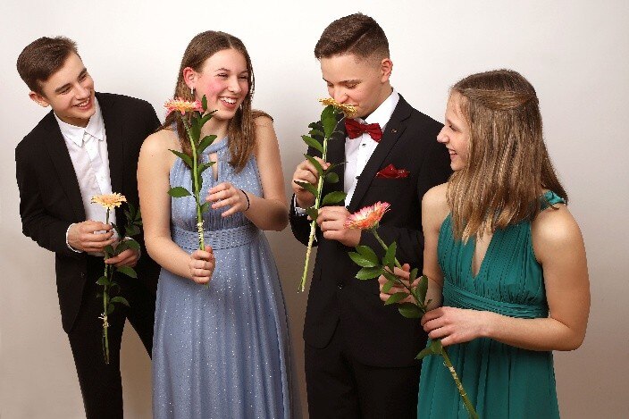 Jugendliche in Festkleidung mit Blumen in der Hand