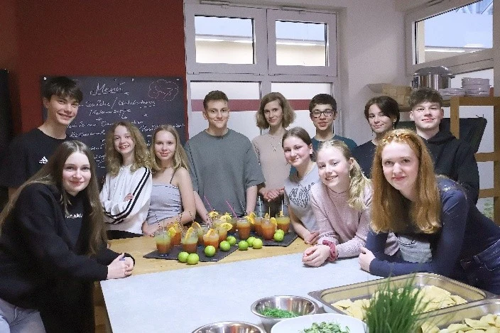 Jugendliche stehen um einen Tisch und lächeln