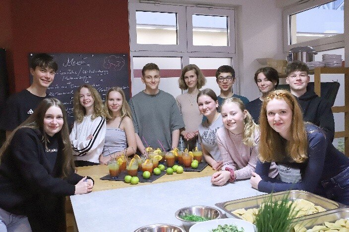Jugendliche stehen um einen Tisch und lächeln