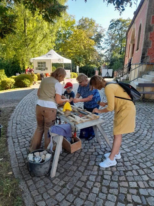 Kinder und Erwachsene stehen um einen Tisch und arbeiten mit Holz