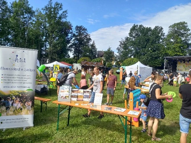 Infostand von Alisa – Alleinerziehend in Sachsen auf einer Open-Air-Veranstaltung mit Besuchern, Flyern und Spielangeboten für Kinder.